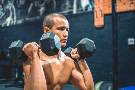 Portrait of young sportsman working out with weights at gym.の写真素材