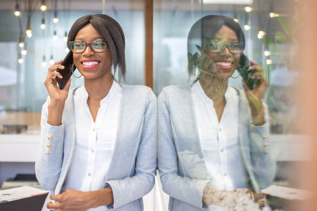 Young african american businesswoman talking on mobile phone in modern office.の写真素材