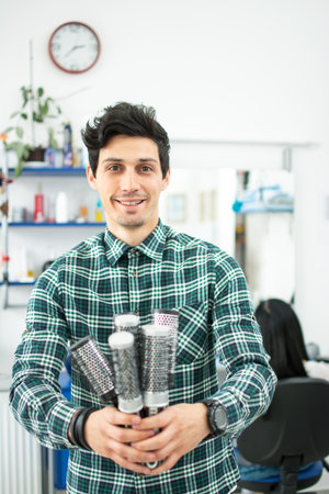 Young male hairdresser holding many combs and showing it to the camera.の写真素材