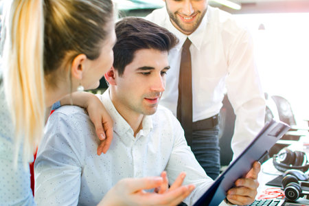 Young businessman looking at business report surrounded by business colleagues in the office.の写真素材