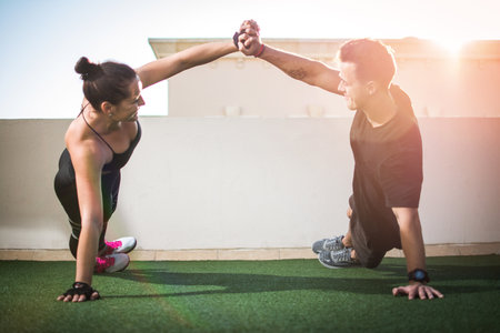 Young sporty couple working out together at outdoor gymの写真素材