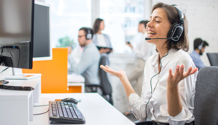 Positive female customer services agent with headset working in call centerの写真素材