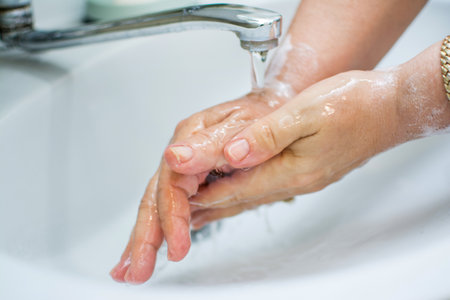 Woman washing hands with soap under the faucet with water. Washing hands for daily personal care against pandemic.の写真素材