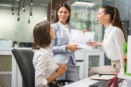 Business women discussing the charts and graphs showing the results of their successful teamwork at business meetingの写真素材