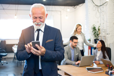 Senior businessman using cellphone in a officeの写真素材