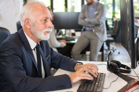 Senior businessman in formalwear working on computer in officeの写真素材