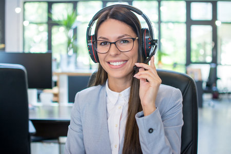 Friendly female helpline operator with headset in office