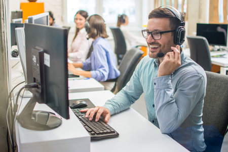Confident male customer support operator with headset working in call centerの写真素材