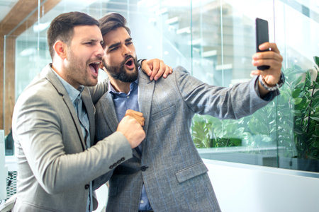 Two handsome business colleagues taking a selfie photo in officeの写真素材