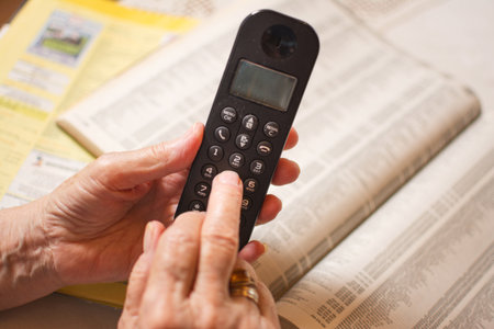 Close up of old wrinkled hands dialing a phone number from address book.の写真素材