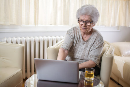 Concentrated senior woman using laptop at home