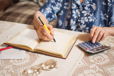 Unrecognizable senior woman calculating financial bills at home.の写真素材