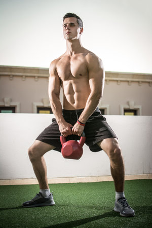 Muscular young sporty man workout with weight outdoorsの写真素材