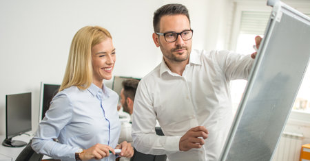 Two young business people discussing in front of flipchart.の写真素材