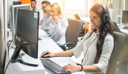 Young smiling female employee talking with the client in call center.