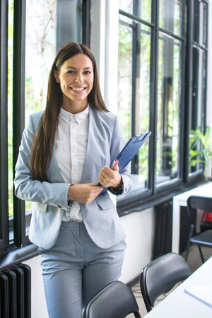 Young businesswoman holding clipboard in office