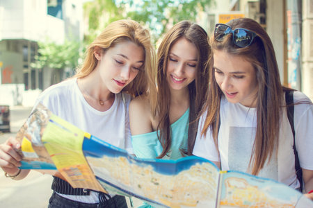 Teenage girls searching for direction on the map outdoors
