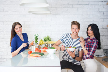 Young people preparing healthy meal at kitchen.の写真素材