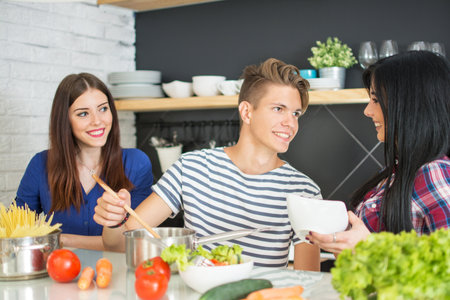 Three young friends talking in the kitchen.の写真素材