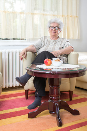 Senior woman relaxing in armchair at homeの写真素材