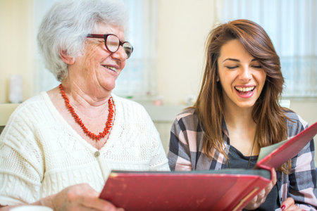Grandmother and granddaughter looking at old photos at photo album.の写真素材
