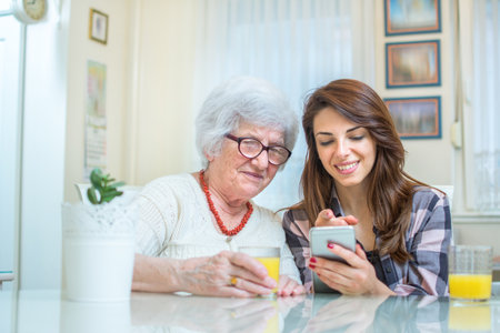 Young woman showing something on mobile phone to grandmother.の写真素材
