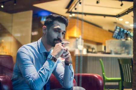 Worried or pensive business man sitting in sofa at cafe and looking away.の写真素材