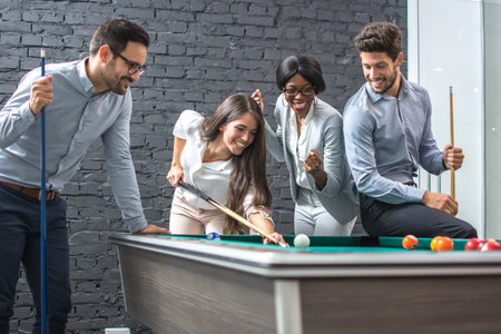 Happy business people playing billiards during office break