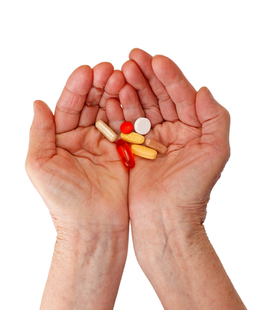 Elderly woman holding pills in her handsの写真素材