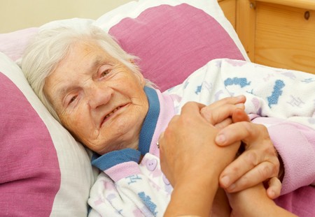 Happy elderly woman holding daughters hand in the bedの写真素材