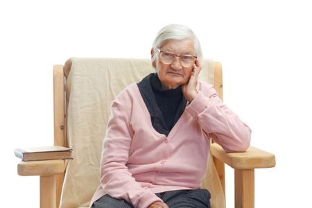 Portrait of a lonely elderly woman sitting in a fotelの写真素材