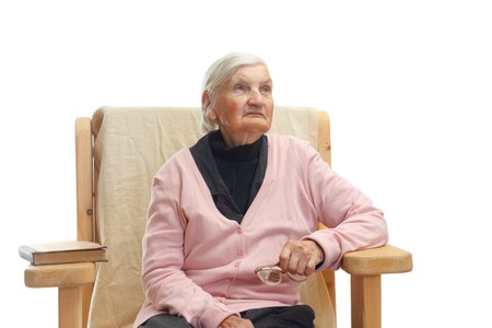 Portrait of a lonely elderly woman sitting in a fotelの写真素材