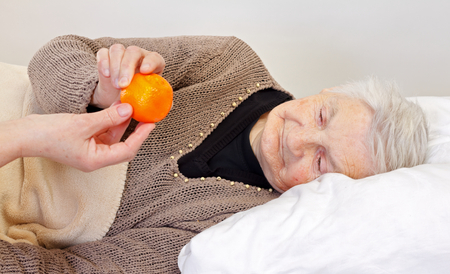 Elderly wrinkled woman laying in the bedの写真素材