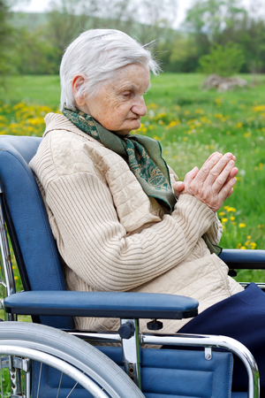 Handicapped elderly woman sitting in a wheelchair outdoorの写真素材
