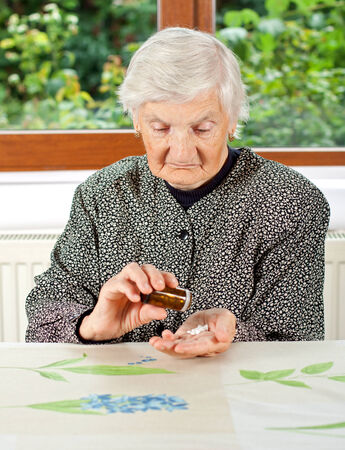 Elderly woman holding pills in her wrinkled handの写真素材