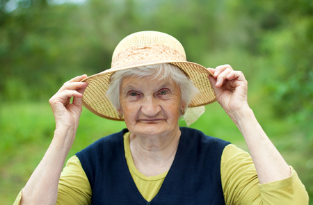 Happy elderly woman with hat in the gardenの写真素材