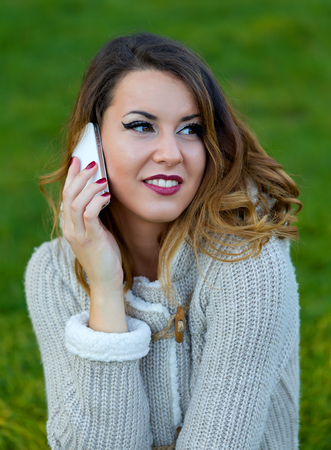 Attractive woman talking on the phone in the parkの写真素材