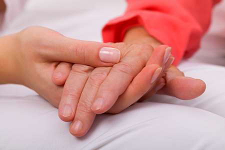 Caregiver holding elderly patients hand at homeの写真素材