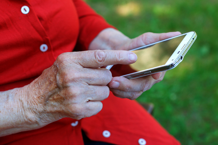 Close up of a wrinkled finger touching a mobilephoneの写真素材