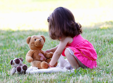 Cute little girl playing with her teddy bearの写真素材
