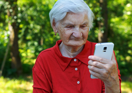 Beautiful elderly woman looking at a smartphoneの写真素材