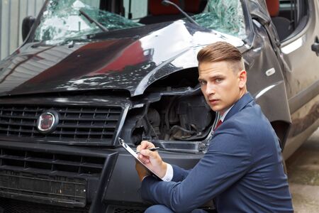 Well dressed insurance assessor inspecting damaged vehicleの写真素材