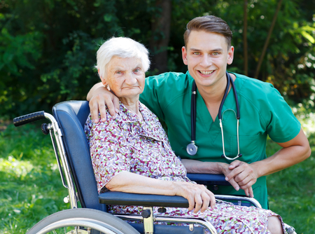 Young doctor helping a handicapped elderly womanの写真素材