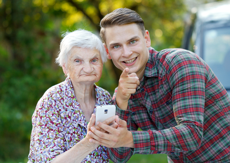 Grandmother and grandson using a white smartphoneの写真素材