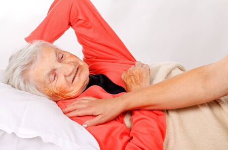 Caregiver holding elderly patients hand at homeの写真素材