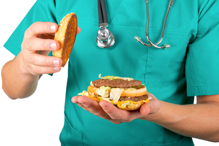 Photo of a doctor's hand holding a cheeseburgerの写真素材