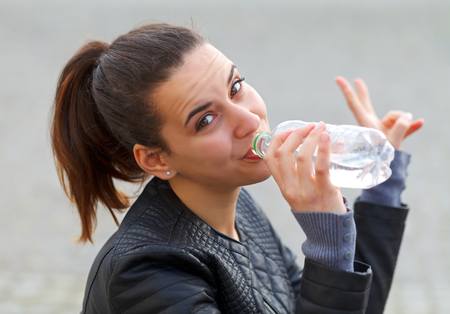 Photo of a thirsty young woman drinking waterの写真素材