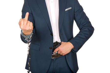 Handcuffed man in suit show middle fingerの写真素材