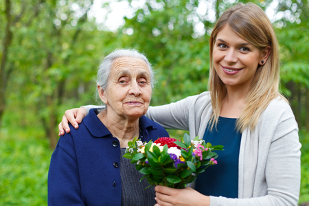 Portrait of a happy senior woman, receiving flowers from her granddaughterの写真素材
