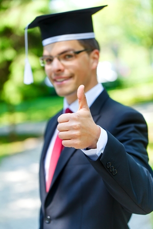 Happy graduateing student wearing graduation  hat ans showing thumbs upの写真素材